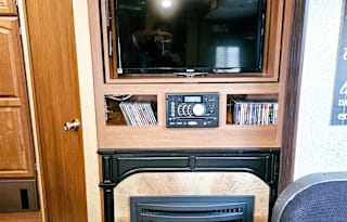 Large RV with outdoor kitchen, fireplace, and TVs