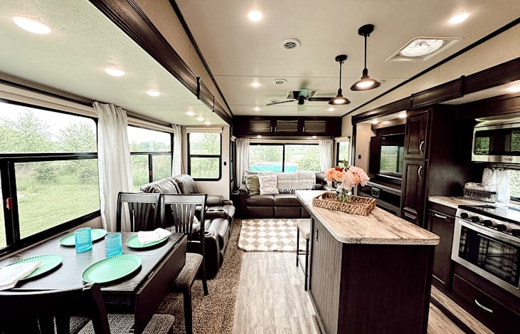 Large living area includes a table & four chairs, reclining theatre seats with heat & massage, and a comfy couch that converts into a queen-sized bed.  Everything has been updated with cute decor.