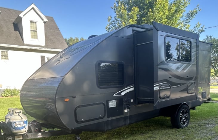 Camper exterior - 2 propane tanks, front pass through storage, water/electric hook up, slide out with storage underneath.