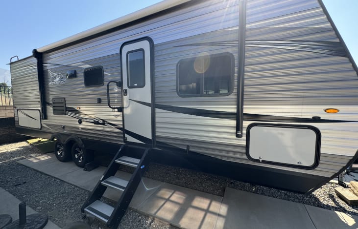 Exterior offers LED lighting, speakers, electric awning, sturdy stair system, and outdoor kitchen that includes 2-burner stove, sink, and refrigerator.
