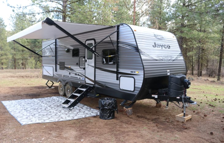 Exterior with solid steps, power awning, outdoor speakers, and outdoor rug.