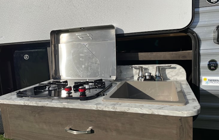 Outdoor cooktop and sink along with a mini fridge.