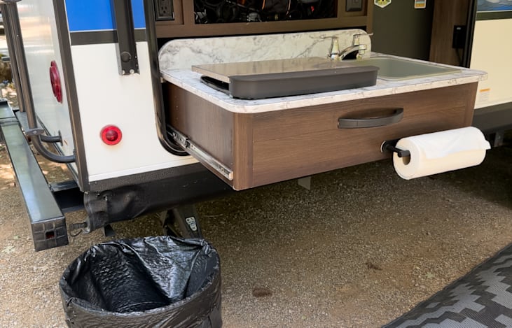 Outdoor Kitchen with propane stove, sink, and drink fridge. Collapsible 30 gallon trash can also provided.