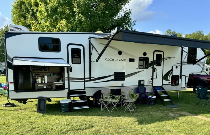 Outside setup with outdoor kitchen, electric griddle, gas grill, trash cans, folding lawn chairs.