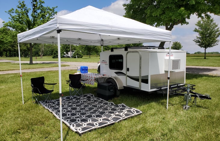 Included 10X10 canopy for keeping you shaded and protected from the rain. Two chairs, table, rug and 7 gallon freshwater dispenser for washing hands and dishes. Optional Electric Cooler shown.
