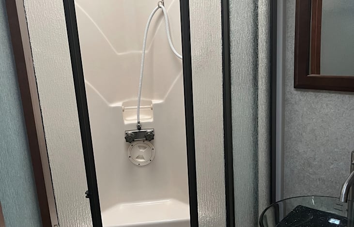 Enjoy the comfort of a spacious walk-in shower with glass doors, a built-in seat, and skylight above—offering plenty of headroom, natural light, and a relaxing, spa-like experience on the road.