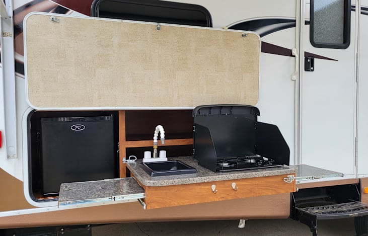 Outdoor kitchen with mini fridge, sink, grill & 2 slide-out counter tops.