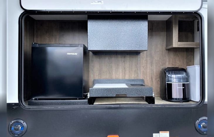 Outdoor kitchen: Ice maker, mini-fridge, bottle opener, and cutting board.