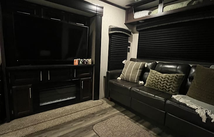 large flat screen tv with fireplace and couch that can be pulled out to make a king-size bed.