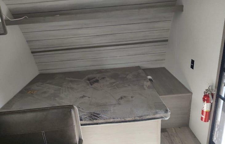 Queen bed in the front. Pillows, sheets and duvet are provided in the storage.