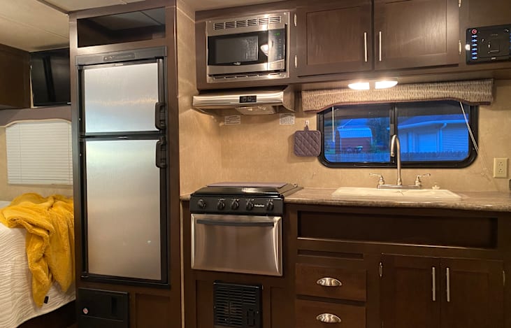 Fully stocked kitchen with 3 burner propane stove, oven, refrigerator/freezer and microwave.