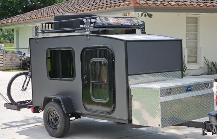 Camping stove, propane tank, portable refrigerator and cooking gear are stored in this water proof metal trunk.
