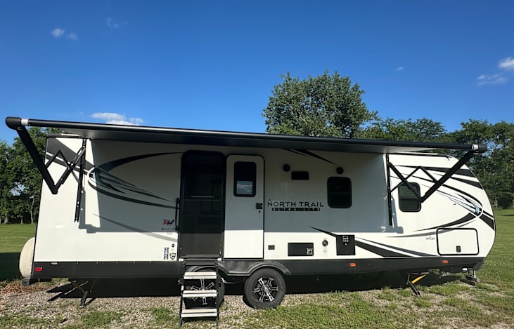 Modern travel trailer with slide and large retractable awning.