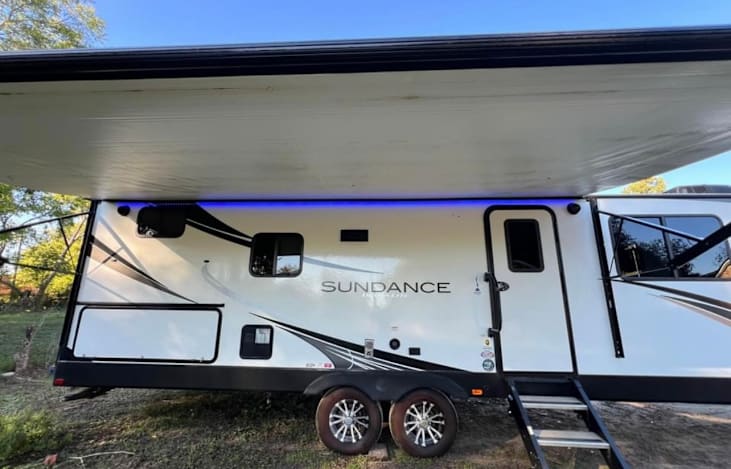 Electric awning with outdoor lighting, outdoor kitchen, and refrigerator
