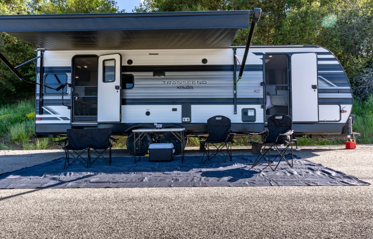 Spacious motorized awning with included chairs, table, and cooler