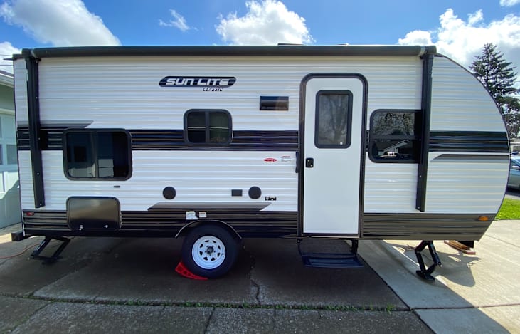 Right side of RV- storage, speaker system, electrical outlet, vent, door and awning (rolled up)