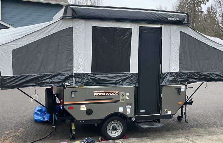 Small lightweight pop up camper has a sturdy door with screen, awning, and place for removable table/grill!
