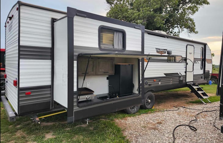 Wildwood camper with outside kitchen that includes sink and refrigerator. Also includes a power awning.