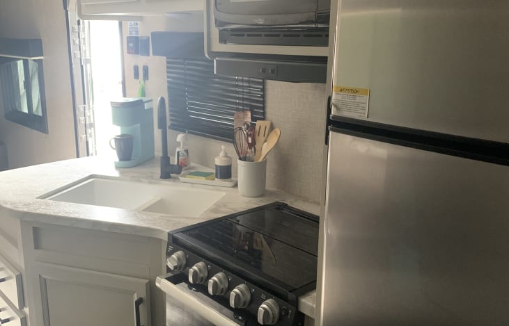 Kitchen with electric fridge, and propane stove oven combo.